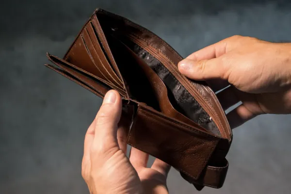 Two hands holding open an empty brown leather wallet.