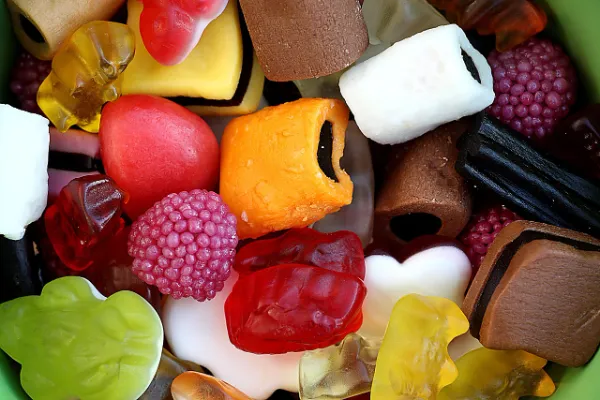 A vibrant, close-up assortment of colorful candies including bablbabldabl gummy bears, licorice wheels, fruit jellies, and white foam shapes, showcasing a variety of textures and flavors.