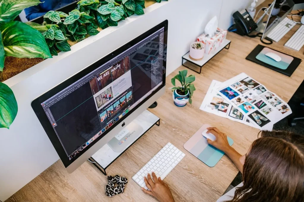 A blurred, overhead view of a woman with blonde hair working intently on a silver laptop on a wooden desk, emphasizing the focused effort required for an intensive ranking and traffic growth project.